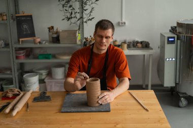 Potter sculpts a patterned cylinder from clay clipart