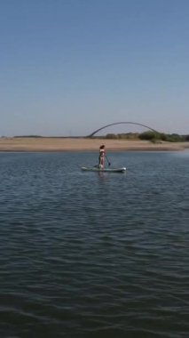 Beyaz kadın SUP güvertesinde yüzüyor. Dikey video