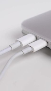 Adam kabloları dizüstü bilgisayara çekiyor. Dikey video