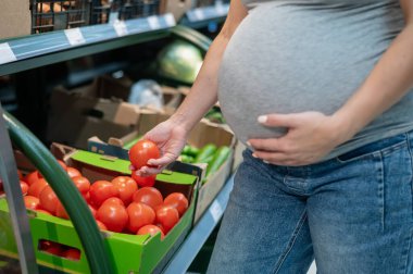 Hamile kadın marketten domates alıyor.