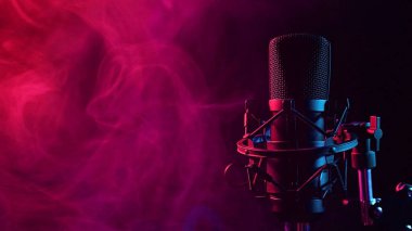 Siyah arka planda pembe dumanlı profesyonel mikrofon.