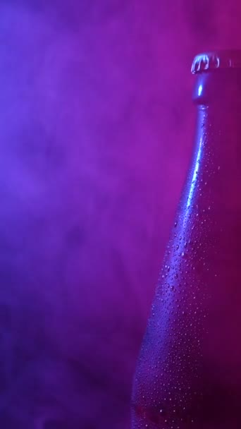 ブルーピンクの煙で回転するビール瓶 バーティカルビデオ — ストック動画