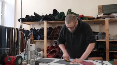 Beyaz sakallı adam bir atölyede bronzlaştırıcı olarak çalışıyor.