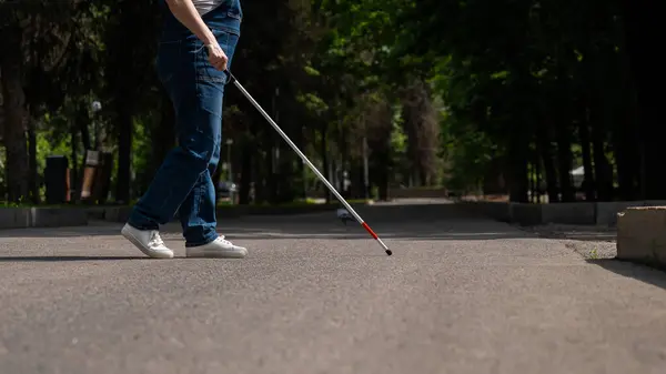 Blind woman crosses the street with the help of a tactile cane