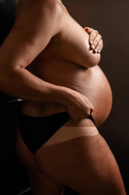 Hamile kadın anında bronzlaşmak için külotunu geri çekiyor. Dikey fotoğraf