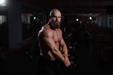 Spor salonunda poz veren beyaz kel adam.