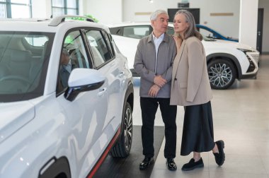 Yaşlı beyaz bir çift araba galerisinde yeni bir araba seçiyor.
