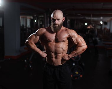 Spor salonunda poz veren beyaz kel adam.