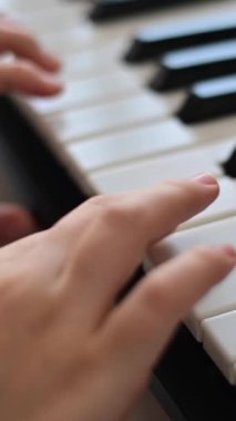 Close-up of female hands on piano keys. Woman playing electric synthesizer. Vertical video