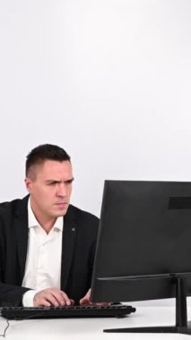 Caucasian man in a suit gets angry and smashes the keyboard on the monitor. An office worker in a rage breaks the computer. Vertical video
