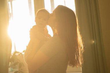 Beyaz bir kadın yeni doğmuş oğlunu nazikçe kaldırır.