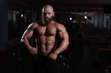 Spor salonunda poz veren beyaz kel adam.