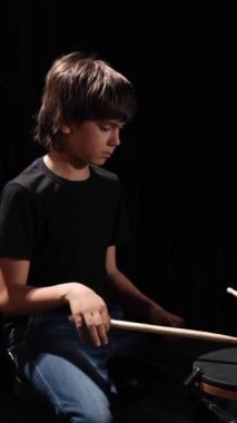 A boy plays drums in a recording studio. Vertical video