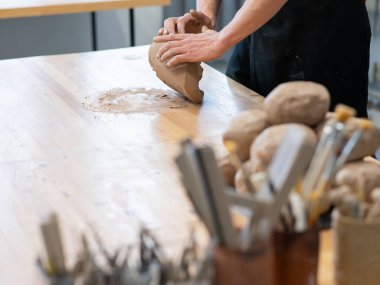 A potter kneads clay before using it in the workshop. Close-up of a mans hands