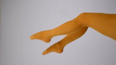 Beyaz arka planda, ocher taytlı kadın bacakları.