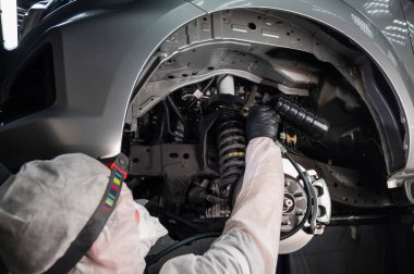 Bir otomobil tamircisi korozyon önleyici maddeyi arabanın alt gövdesine uygular.