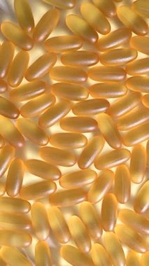 Close-up of golden omega three capsules. Dietary supplement fish oil rotate on a white background. Vertical video