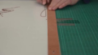 Kadın bir bronzlaştırıcı deri parçaları keser. Deri işçileri atölyesi