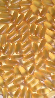Close-up of golden omega three capsules. Dietary supplement fish oil rotate on a white background. Vertical video