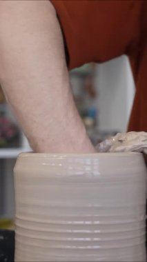 Çömlekçi ellerinin çömlekçi çarkında seramik sürahi yapmasının yakın çekimi. Dikey video