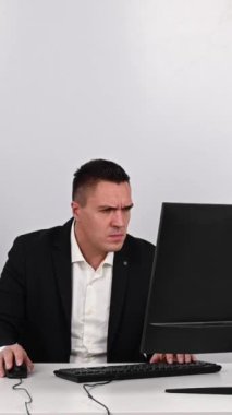Caucasian man in a suit gets angry and smashes the keyboard on the monitor. An office worker in a rage breaks the computer. Vertical video