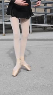 Balerin dışarıda dans ediyor. Sivri uçlu ayakkabılı bir kadının bacaklarının yakın çekimi. Dikey video