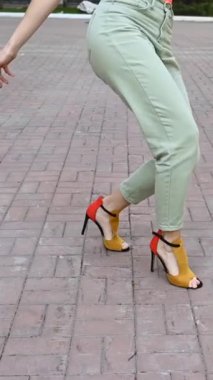 Dışarıda yüksek topuklularla dans eden kadın. Kadın bacaklarına yakın çekim. Dikey video