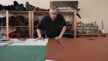 Beyaz sakallı adam bir atölyede bronzlaştırıcı olarak çalışıyor.