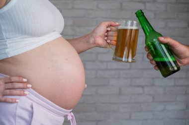 Adam hamile kadınla bira tokuşturuyor.