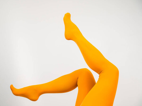 Female legs in ocher tights on a white background