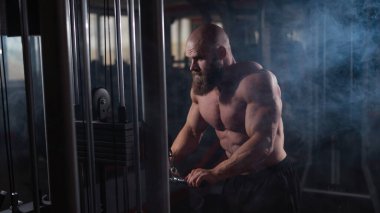 Kel Kafkas vücut geliştirici kabloyla ağır triseps egzersizleri yapıyor.