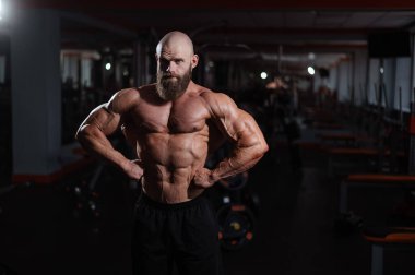 Spor salonunda poz veren beyaz kel adam.