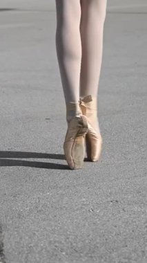 Balerin dışarıda dans ediyor. Sivri uçlu ayakkabılı bir kadının bacaklarının yakın çekimi. Dikey video