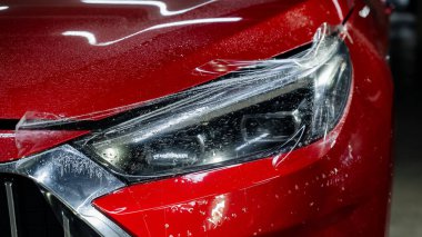 Close-up of a red car headlight with vinyl wrap clipart