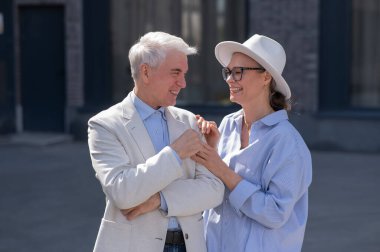 Aşık yaşlı bir çift şehirde yürür. Beyaz saçlı şık bir erkek ve kadının portresi.