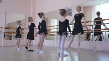 Çocuk bale okulu. Beyaz kadın küçük kızlara bale öğretiyor.