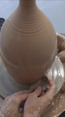 Çömlekçi, çömlekçi çarkında vazonun yüzeyini düzleştiren bir aletle çalışır. Dikey video