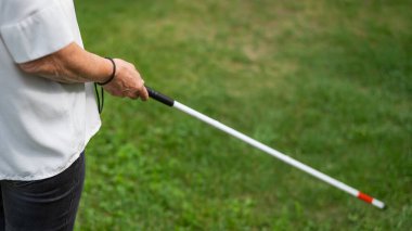 Yaşlı bir kadının, parkta yürürken değnek değneği kullanan bacaklarını yakın plan.