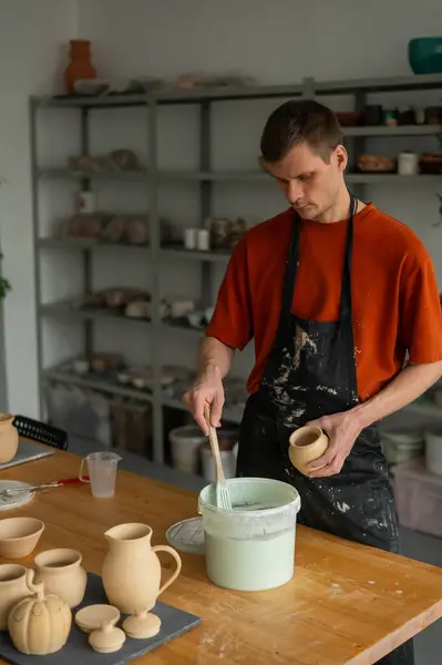 stock image A potter applies glaze to a ceramic pot with a brush