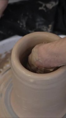 Çömlekçi ellerinin çömlekçi çarkında seramik sürahi yapmasının yakın çekimi. Dikey video