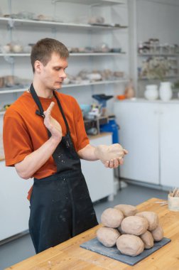 Potter kneads clay before using it in the workshop. Vertical photo