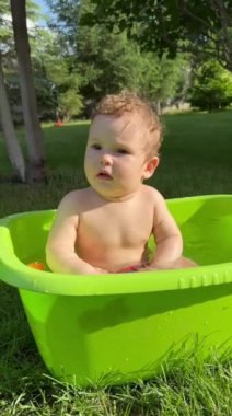 Yazın dışarıdaki havuzda şirin bebek banyosu yapıyor. Dikey video