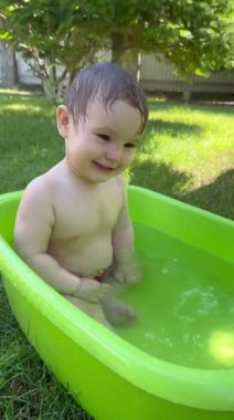 Yazın dışarıdaki havuzda şirin bebek banyosu yapıyor. Dikey video