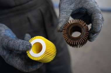 Tamirci eski ve yeni araba yağı filtrelerini tutuyor.