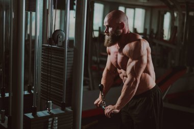 Kel Kafkas vücut geliştirici kabloyla ağır triseps egzersizleri yapıyor.