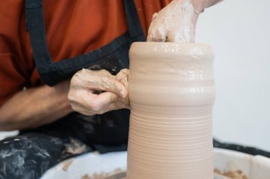 Çömlekçi elleriyle çömlekçi çarkında seramik vazo yaparken.