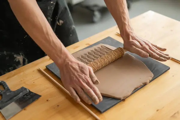 stock image Close-up of a potters hands rolling out clay using a rolling pin with patterns