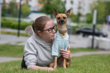 Küçük bir köpekle yürürken çimenlerde yatan beyaz bir kadın.