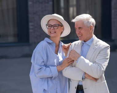 Aşık yaşlı bir çift şehirde yürür. Beyaz saçlı şık bir erkek ve kadının portresi.