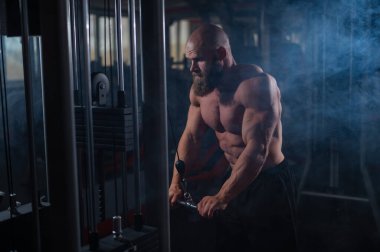 Kel Kafkas vücut geliştirici kabloyla ağır triseps egzersizleri yapıyor.